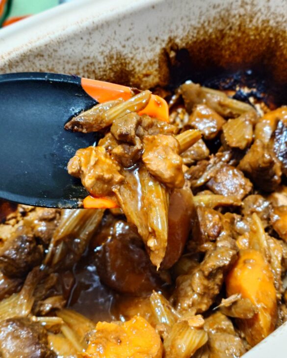 Gęsty, lśniący gulasz wołowy z marchewką w kremowym naczyniu ceramicznym Le Creuset.