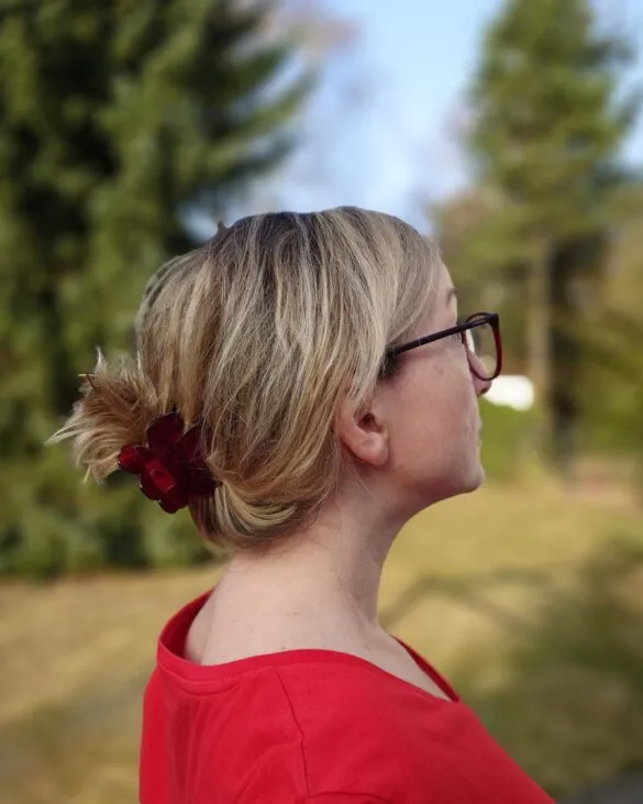 Profil kobiety z włosami blond do ramion, spiętymi klamrą w kok. Zdjęcie w świetle dziennym pokazuje blask i teksturę włosów po balejażu.
